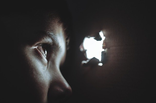 Boy looking through hole in the wall